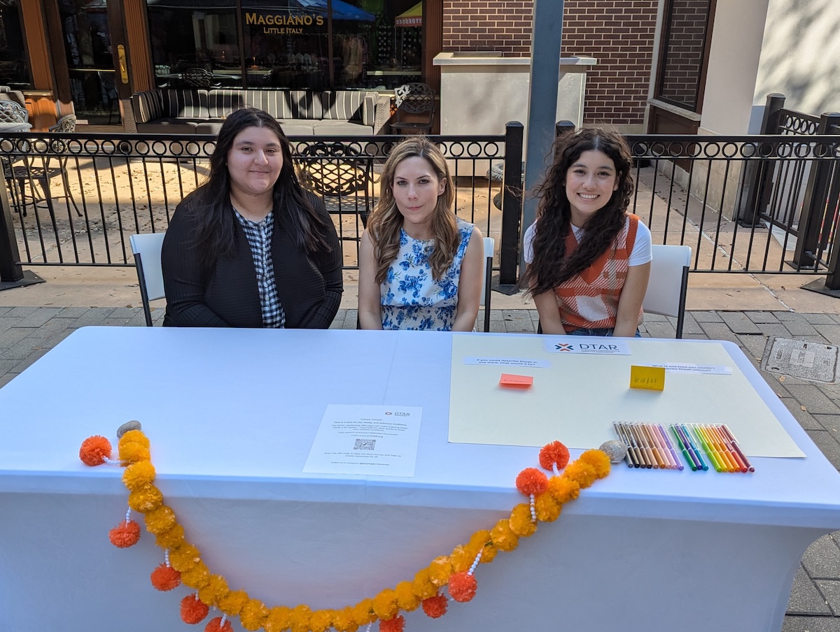 DTAR team members at community outreach table with informational materials and marigold decorations